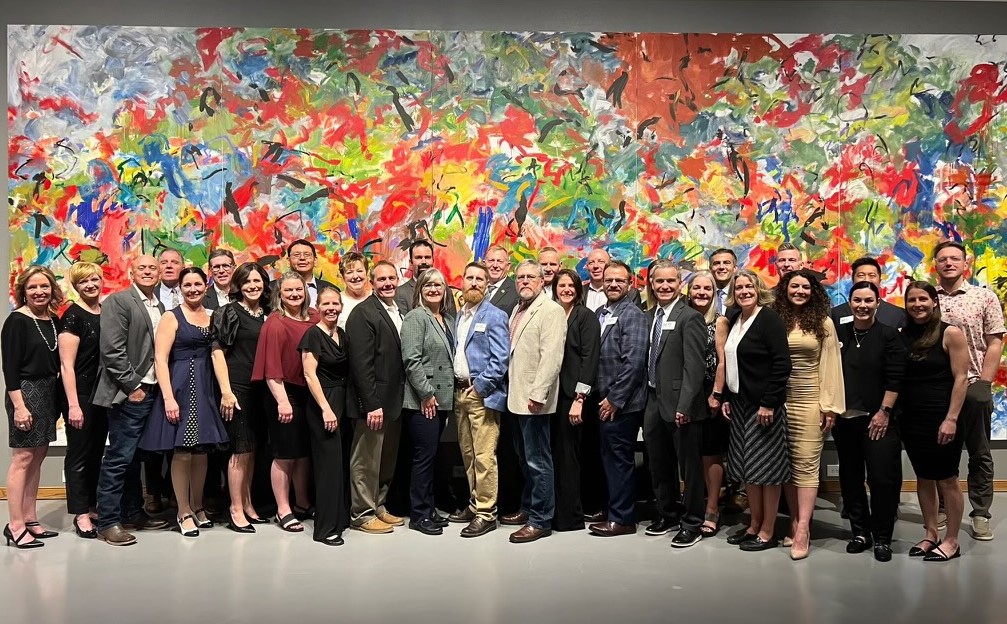 Group of people standing in front of abstract wall art at The Wyoming Academy inaugural class graduation.