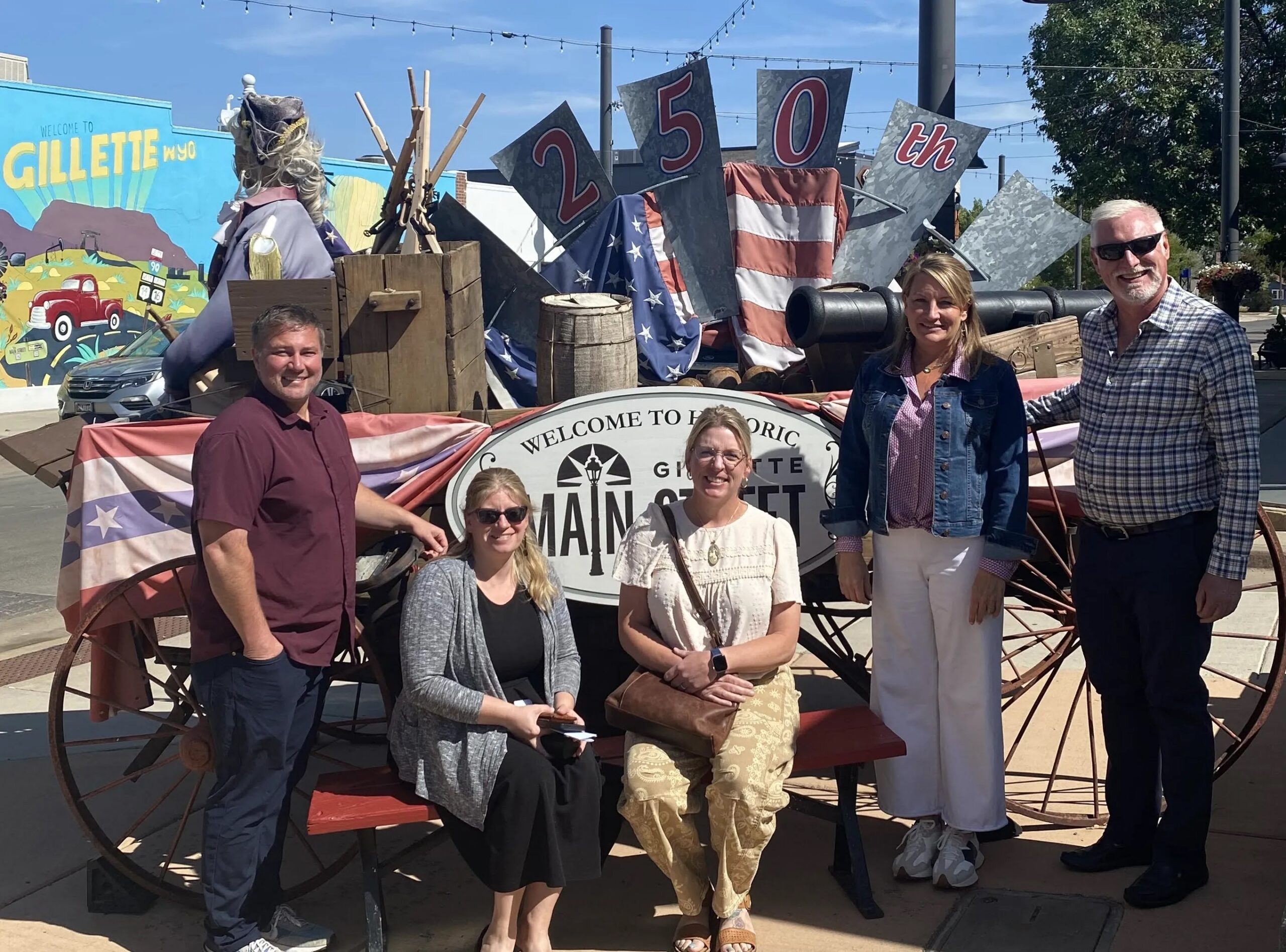 Members of the Wyoming Main Street Advisory Board gather together in from of a sign in downtown Gillette, Wyoming.