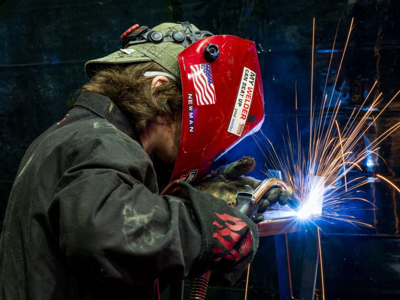 Photo of welder in a red welding helmet